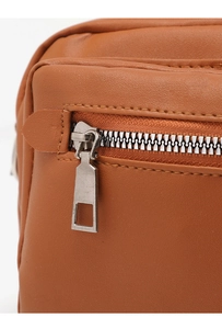 Macro shot of silver metal zipper and precise stitching on brown faux leather handbag