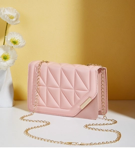Detail of pink quilted crossbody bag with golden chain strap and magnetic lock