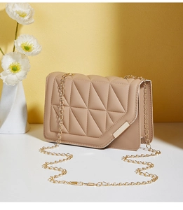 Detail of light beige quilted crossbody bag with gold chain strap and magnetic lock
