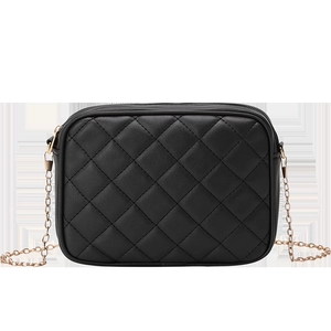 Detail of black quilted crossbody bag with rhombic pattern and gold metal chain strap