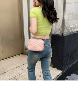Detailansicht der rosa gesteppten Kameratasche mit goldener Kette am Modell