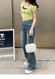 Nahaufnahme der weißen Stepptasche mit Kette und Jeans mit Schmetterlingsbestickung