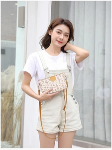 Detail of cream small crossbody bag with letter print and bright yellow shoulder strap