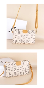 Close-up of cream crossbody bag with brown monogram pattern and bright yellow strap