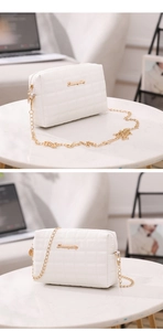 Détail du sac à chaîne blanc matelassé avec logo en métal doré sur table en marbre