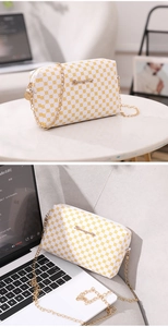 Détail du petit sac blanc avec motif floral jaune et bandoulière en chaîne dorée