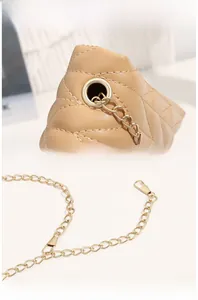 Detail view of the quilted leather texture and light gold metal chain on a beige bag