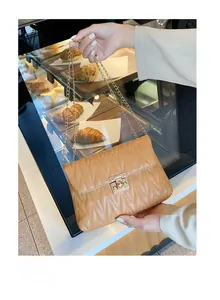 Close-up of caramel wave-quilted shoulder bag with golden chain and rectangular lock