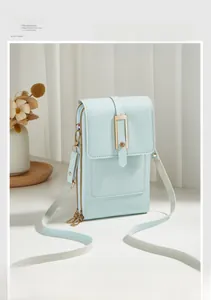 Detail view of mint blue litchi pattern leather phone bag with gold clasp and dual zippers