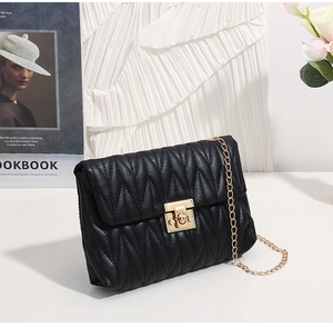 Close-up of black quilted shoulder bag with golden twist lock and metal chain strap