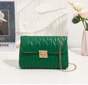 Detailed view of green quilted leather bag with gold metal clasp and chain strap