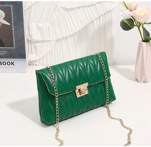 Close-up of green crossbody bag with V-shaped stitching and golden metal twist lock