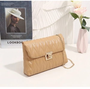 Detailed close-up of beige quilted crossbody bag with gold chain and rotary lock