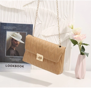 Close-up of light brown shoulder bag with V-shaped quilting and golden chain strap