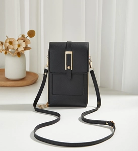 Detail of black pebbled leather phone bag with elegant gold metal buckle and strap