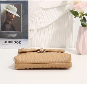Close-up of quilted camel brown leather bag with golden metal twist lock and V-stitch pattern