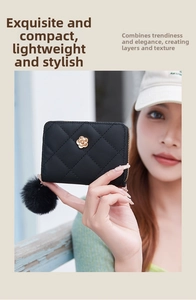 Detail of black quilted wallet with gold flower accent and fluffy fur pompom charm