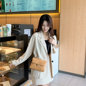 Chic quilted chain bag with gold lock closure worn with a stylish beige blazer suit