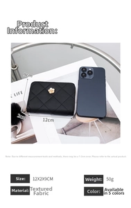 Detail shot of black quilted mini wallet with fur pompom and flower charm beside phone