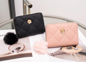Detailed close-up of quilted wallets featuring camellia metal decor and plush pom pom