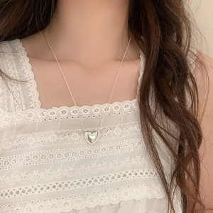 Minimalist silver heart pendant necklace on snake chain worn with elegant lace top