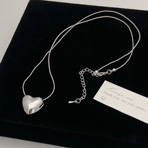 Polished silver heart pendant necklace on a sleek snake chain over a black velvet display