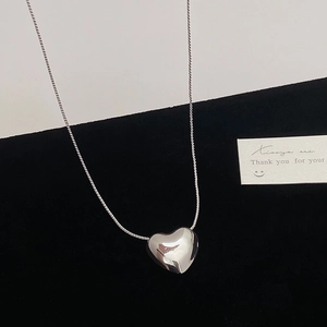 Detailed close-up of a large minimalist heart pendant necklace with polished silver finish