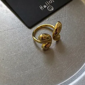 Macro shot of gold-plated open ring with sleek fluid design and polished bean detail