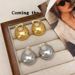 Polished thick teardrop earrings in gold and silver finish on a display tray