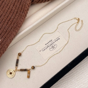 Detail of round tiger eye stone pendant on golden chain with vintage bohemian design