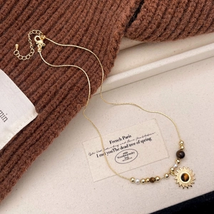 Detailed view of tiger eye stone pendant and golden beads on an elegant sunburst necklace