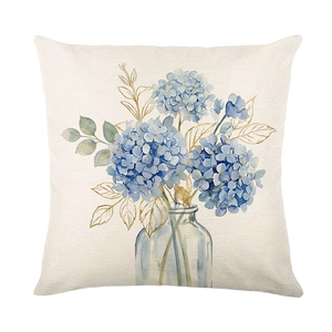 Linen cushion cover with blue hydrangea in glass vase on white background
