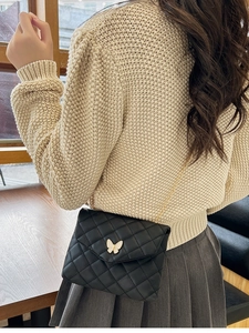 Detail der schwarzen Stepptasche mit weißem Schmetterlingsverschluss und goldener Kette