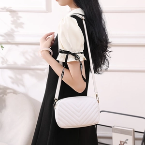 Women's white chevron quilted crossbody bag with gold hardware shown on a model