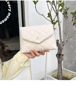 Detail der cremefarbenen Stepptasche mit goldenem Schmetterlingsverschluss und Kette