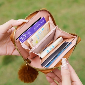 Women's quilted brown leather wallet with pompom charm shown open with interior slots