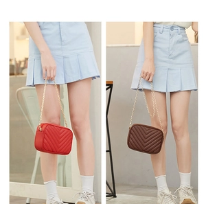 Detail of red and brown V-quilted faux leather crossbody bags with gold chain straps