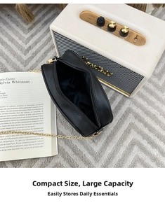 Detail view of the black V-quilt camera bag interior with golden chain strap and lining