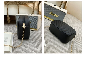 Detail view of the black V-quilted faux leather bag with a gold metal chain strap