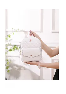 Detail of white quilted mini backpack with small rose floral accents and smooth flap pocket