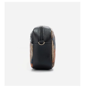 Dettaglio della borsa a tracolla con texture in pelle nera e anello a D dorato laterale