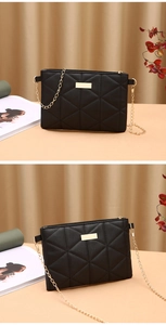 Detail of black quilted crossbody bag with golden chain strap and metallic decoration