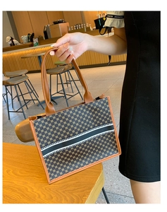 Close-up of vintage tote bag with geometric print and leather handles in a cafe setting