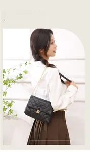 Detail of black quilted crossbody bag with gold chain strap and metal turn-lock closure