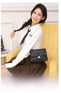 Detail of elegant black quilted crossbody bag with gold chain strap on yellow velvet chair