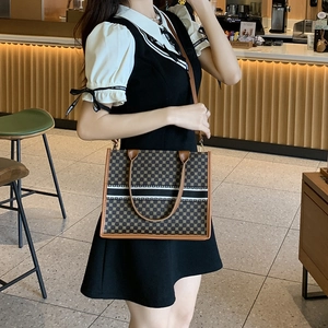 Women's printed tote bag with geometric patterns and brown leather straps in a cafe setting