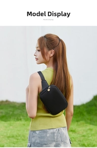 Outdoor close-up of a black minimalist waist bag with elegant gold zipper on a model