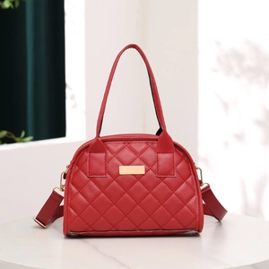 Detail of red quilted faux leather handbag with golden hardware and marble background