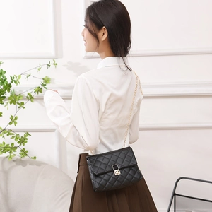 Elegant black quilted crossbody bag with gold chain strap shown on model shoulder