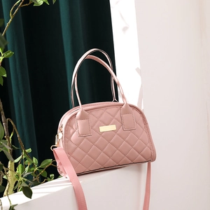 Pink quilted crossbody bag with golden hardware and detachable strap on white stand